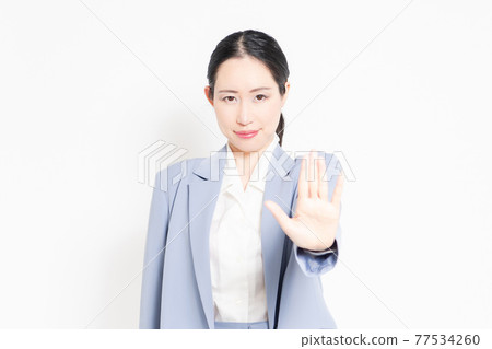 A woman standing in front of a white background and making an NG gesture A woman standing in front of a white background and making an NG gesture 77534260