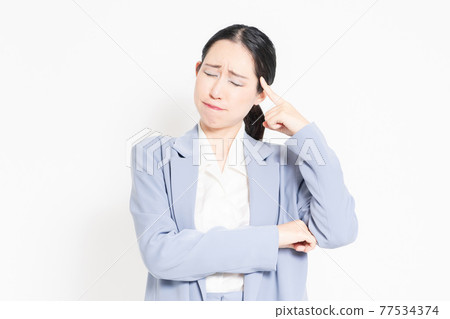 A woman standing in front of a white background and posing to think A woman standing in front of a white background and posing to think 77534374