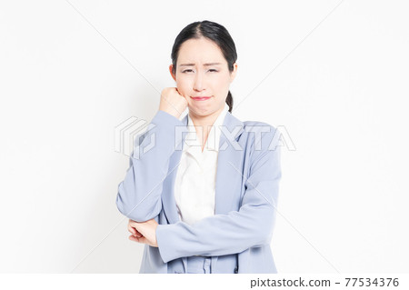 A woman standing in front of a white background and posing to think A woman standing in front of a white background and posing to think 77534376