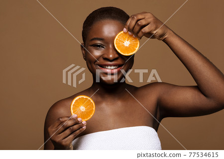 Fruit Acid Peel. Portrait of happy black lady holding two orange slices 77534615