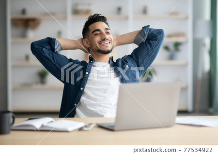 Joyful arab man freelancer having short break Joyful arab man freelancer having short break 77534922