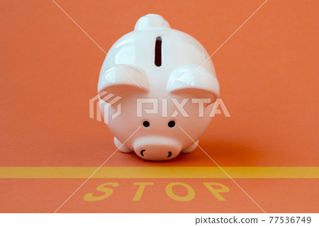 Piggy bank at the edge of a yellow line with a yellow print of the word STOP Piggy bank at the edge of a yellow line with a yellow print of the word STOP 77536749