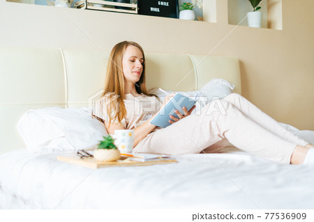 Blonde woman in bed with book Blonde woman in bed with book 77536909