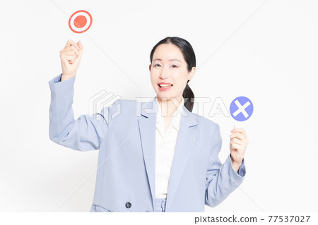 A woman standing in front of a white background and holding an OK and NG placard A woman standing in front of a white background and holding an OK and NG placard 77537027