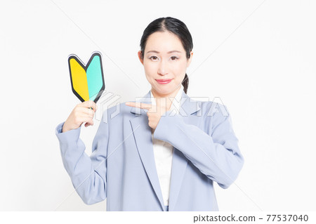 一個站在白色背景前，拿著初學者標記的女人 77537040