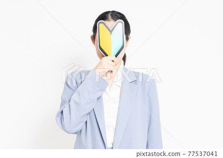 一個站在白色背景前,拿著初學者標記的女人 一個站在白色背景前,拿著初學者標記的女人 77537041