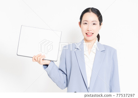 站在白色背景前,拿著一本小寫生簿的女人 站在白色背景前,拿著一本小寫生簿的女人 77537297