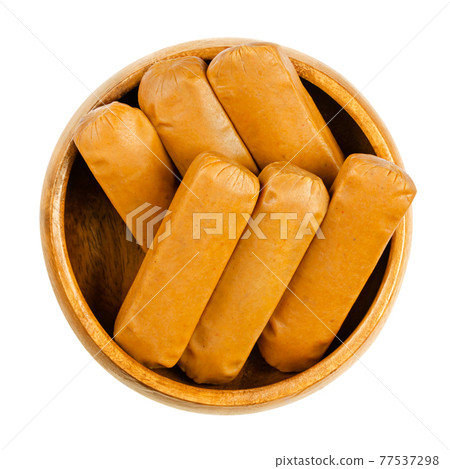 Vegan mini weenies, in a wooden bowl. Six small smoked sausages, made of saitan, a wheat gluten. Also called Wiener or Frankfurter Wuerstl. Close-up, from above, isolated over white, macro food photo. 77537298