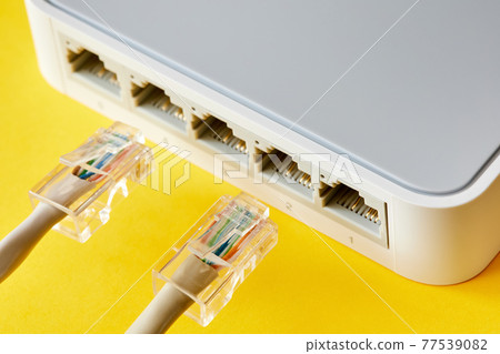Ethernet cables connected to Desktop Switch or routerboard on a yellow background. Close-up, selective focus Ethernet cables connected to Desktop Switch or routerboard on a yellow background. Close-up, selective focus 77539082
