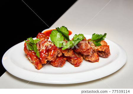 Sesame fried chicken wings with sauce and parsley. Close-up, selective focus. 77539114