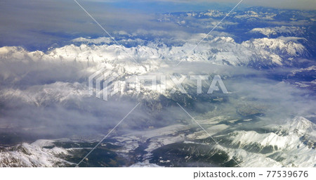 Flying over the snowy mountains 77539676