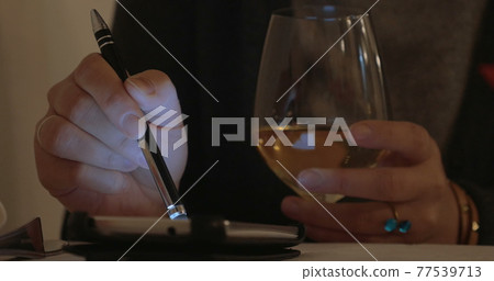 Woman having wine and using cell phone Woman having wine and using cell phone 77539713