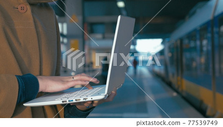 Girl working with laptop at the railway station 77539749