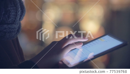 Woman chatting on touch pad outdoor in the evening 77539768