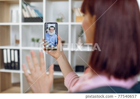 Woman greeting grandfather during video call on smartphone Woman greeting grandfather during video call on smartphone 77540657