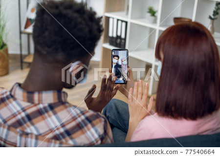 Couple in face masks having video call with muslim friends 77540664