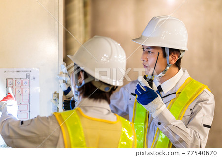 Workers inspecting switchboards at construction sites Workers inspecting switchboards at construction sites 77540670