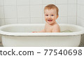 Little happy toddler bathes in a bathtub 77540698