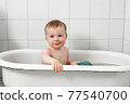 Little happy toddler bathes in a bathtub 77540700