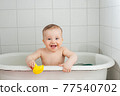 Little happy toddler bathes in a bathtub 77540702