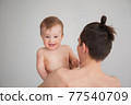 father holding a cute little smiling baby in his arms on a white background 77540709