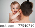 father holding a cute little smiling baby in his arms on a white background 77540710