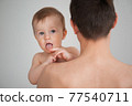 father holding a cute little smiling baby in his arms on a white background 77540711
