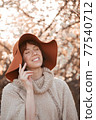 Young smiling girl in a hat on a background of flowering trees 77540712