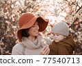 Mom holds the baby against the background of flowering trees 77540713