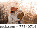 Mom holds the baby against the background of flowering trees 77540714