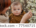 Mom holds the baby against the background of flowering trees 77540715