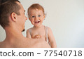 father holding a cute little smiling baby in his arms on a white background 77540718