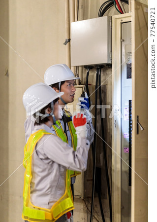 Workers inspecting switchboards at construction sites 77540721