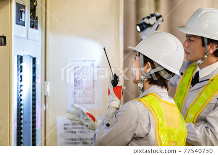 Workers inspecting switchboards at construction sites 77540730