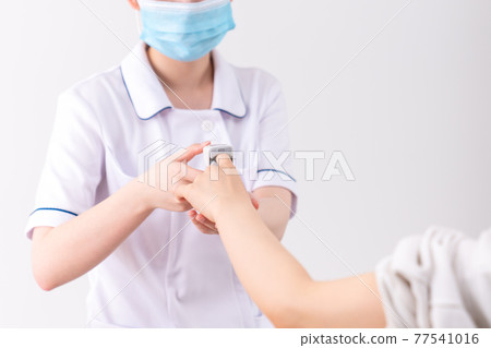 A nurse measuring saturation with a pulse oximeter A nurse measuring saturation with a pulse oximeter 77541016