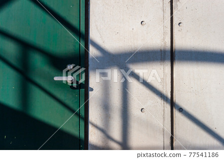 Green iron doors, white concrete walls, and shadows on them Green iron doors, white concrete walls, and shadows on them 77541186