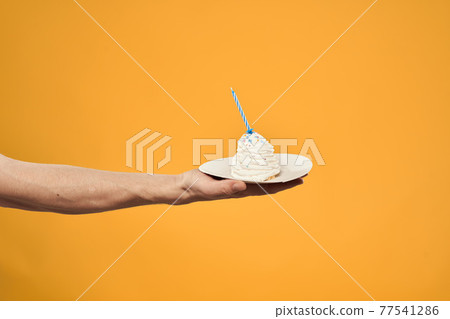 Cake with a candle in a man's hand on a yellow background cropped view Copy Space Cake with a candle in a man's hand on a yellow background cropped view Copy Space 77541286