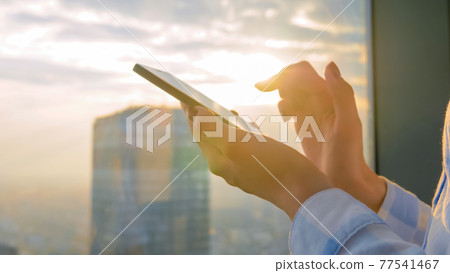 Woman using smartphone device against cityscape view at sunset - close up view Woman using smartphone device against cityscape view at sunset - close up view 77541467