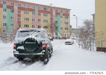 Off-road car on a snowy road in the yard after a snowfall 77542925