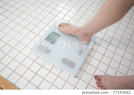A woman measuring weight A woman measuring weight 77543662