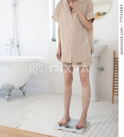 A woman measuring weight 77543664