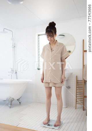 A woman measuring weight A woman measuring weight 77543666