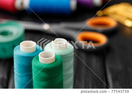 Colorful sewing utensils on black wooden surface Colorful sewing utensils on black wooden surface 77543739