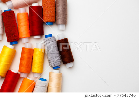 Colored spools of threads on white background Colored spools of threads on white background 77543740