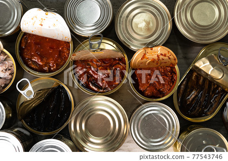 Top view of opened cans with fish conserves on wooden background 77543746