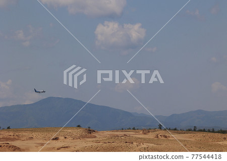 An airplane taking off by grabbing the Tottori Sand Dunes 77544418
