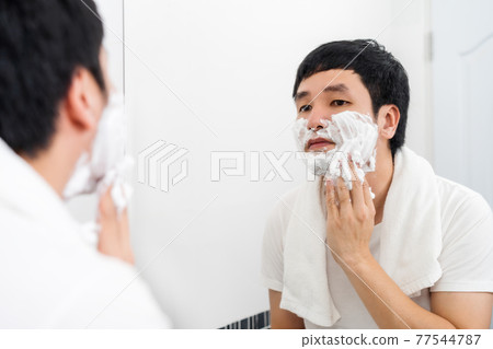 man applying foam cream on face before shaving in the bathroom mirror man applying foam cream on face before shaving in the bathroom mirror 77544787