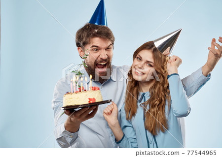 Emotional man with cake and pretty woman party disco blue background Emotional man with cake and pretty woman party disco blue background 77544965