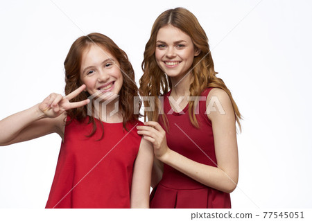 Cheerful mom and daughter next to red dresses hugs lifestyle light background smile 77545051