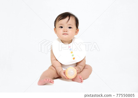 坐在白色背景上的女嬰。成長、健康、能量、育兒形象 坐在白色背景上的女嬰。成長、健康、能量、育兒形象 77550805